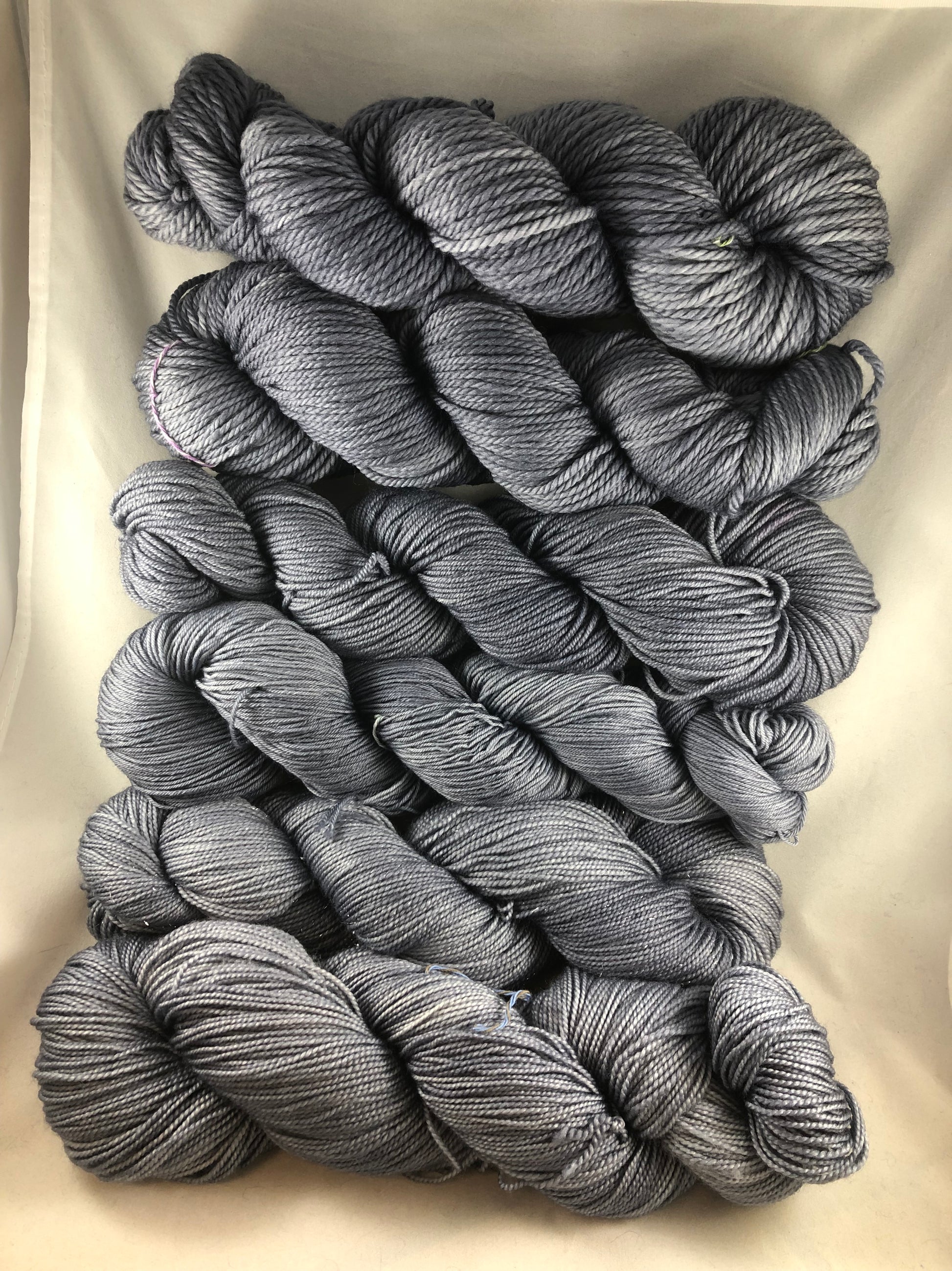 Bundles of dark silvery grey semi-solid yarn laid out against a neutral background.